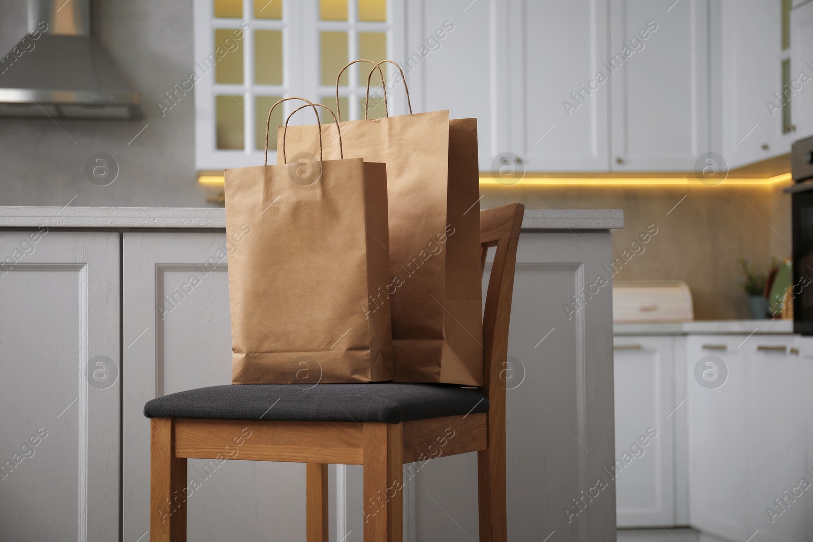 Photo of Paper bags on chair in kitchen. Space for text