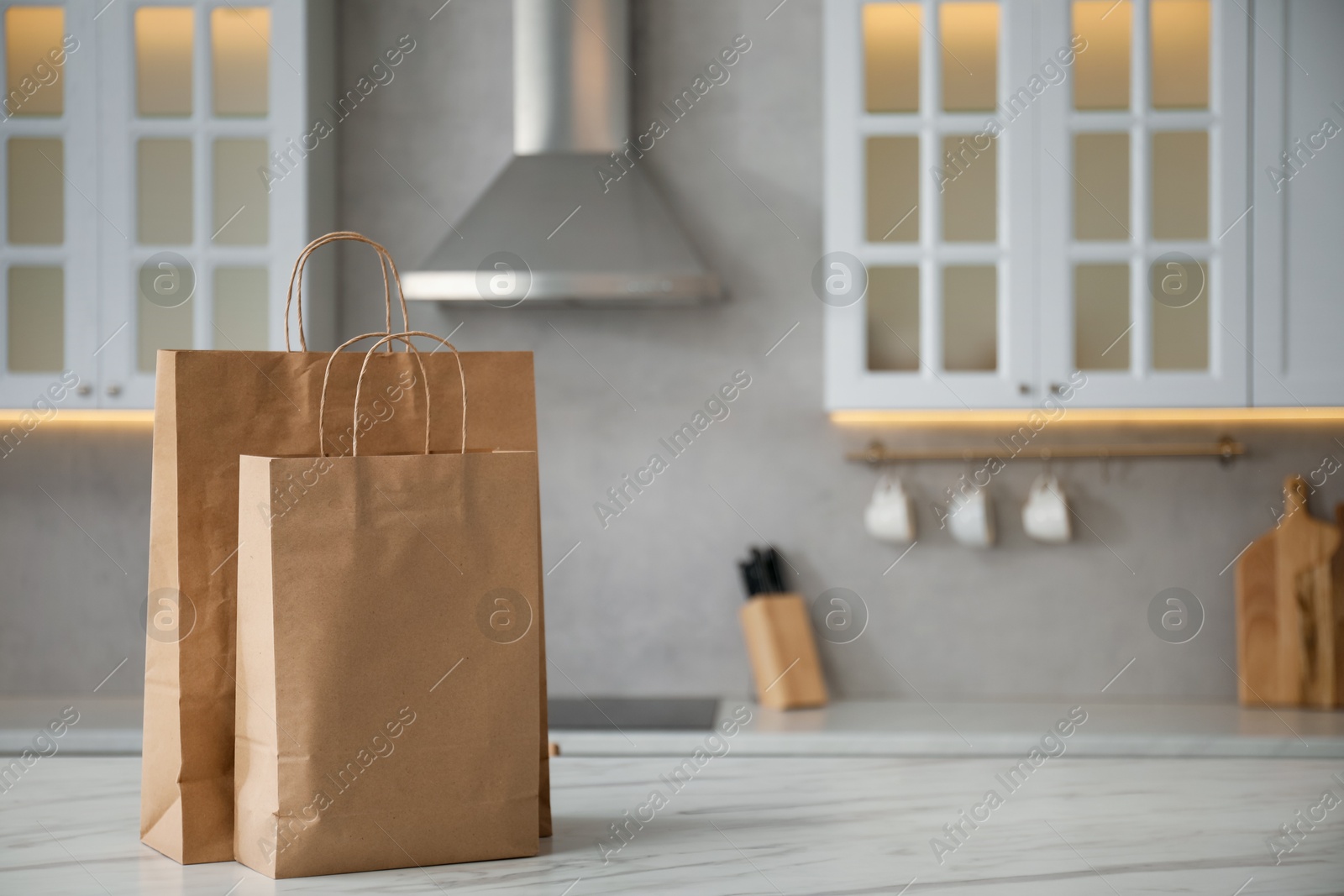 Photo of Paper bags on white marble table in kitchen. Space for text
