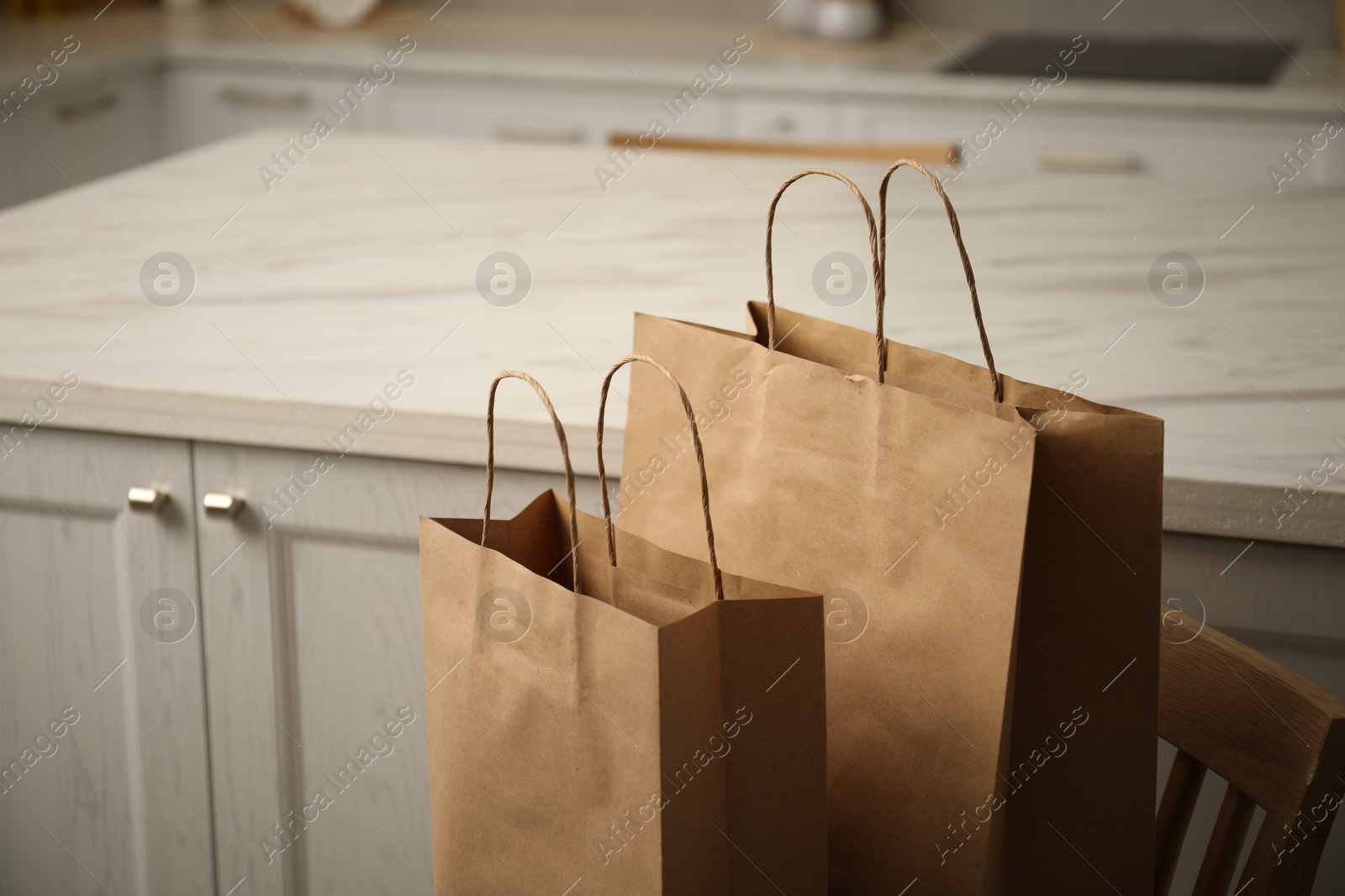 Photo of Paper bags on chair in kitchen, closeup. Space for text