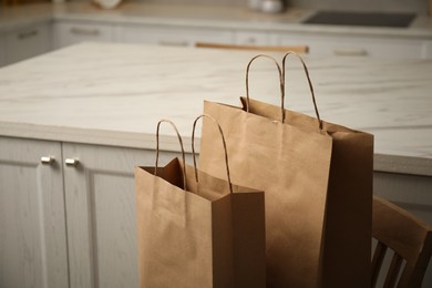 Photo of Paper bags on chair in kitchen, closeup. Space for text