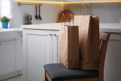 Photo of Paper bags on chair in kitchen. Space for text