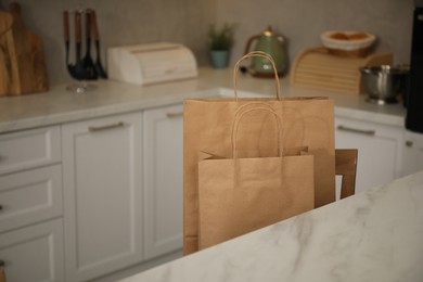 Photo of Paper bags on chair in kitchen, closeup. Space for text