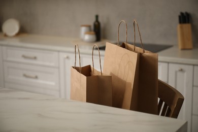 Photo of Paper bags on chair in kitchen, closeup. Space for text
