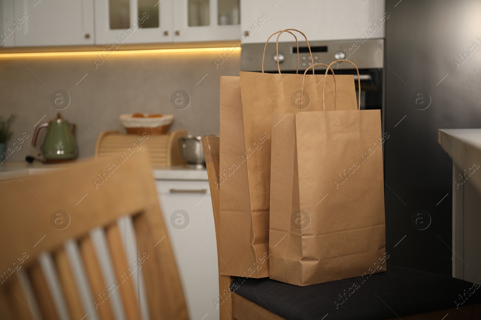 Photo of Paper shopping bags on chair in kitchen