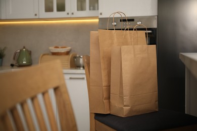 Photo of Paper shopping bags on chair in kitchen