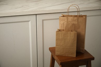 Photo of Paper bags on stool in kitchen. Space for text