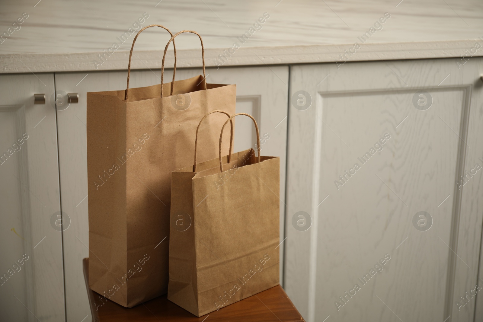 Photo of Paper bags on stool in kitchen. Space for text