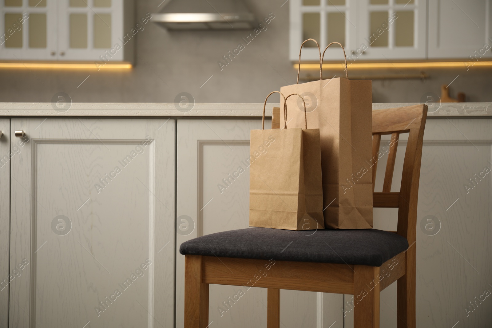 Photo of Paper bags on chair in kitchen. Space for text