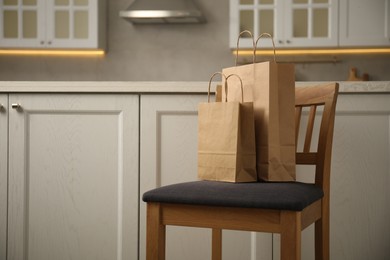 Photo of Paper bags on chair in kitchen. Space for text