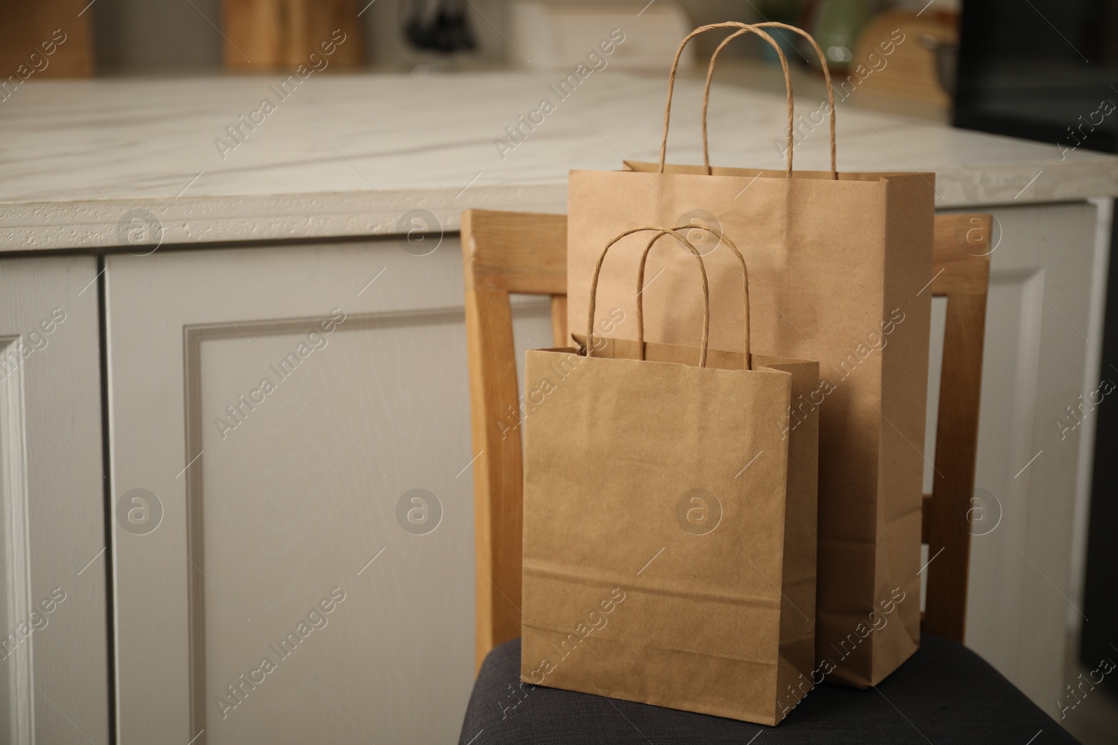 Photo of Paper bags on chair in kitchen. Space for text