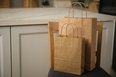 Photo of Paper bags on chair in kitchen. Space for text