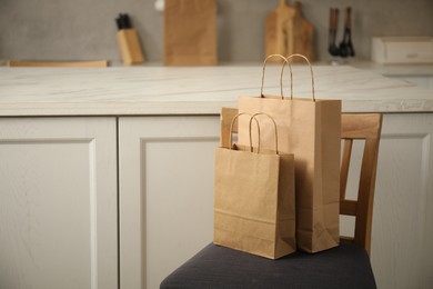 Photo of Paper bags on chair in kitchen. Space for text