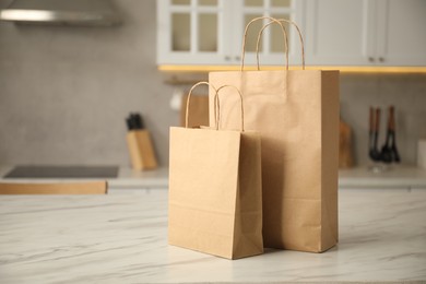 Photo of Paper bags on white marble table in kitchen. Space for text