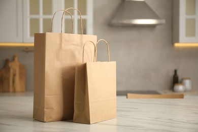 Photo of Paper bags on white marble table in kitchen. Space for text