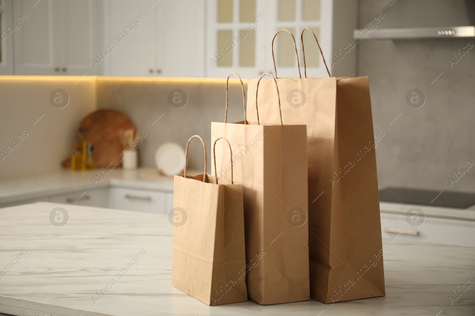 Photo of Paper bags on white marble table in kitchen. Space for text