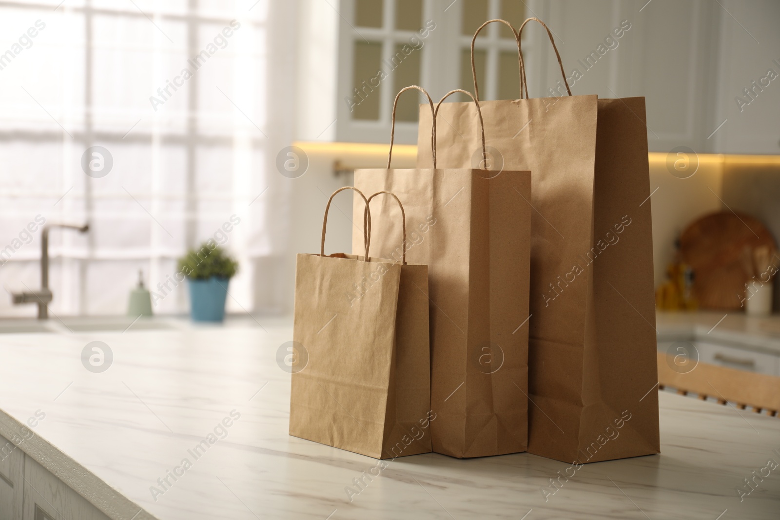 Photo of Paper bags on white marble table in kitchen. Space for text