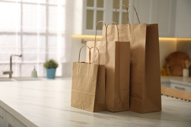 Photo of Paper bags on white marble table in kitchen. Space for text