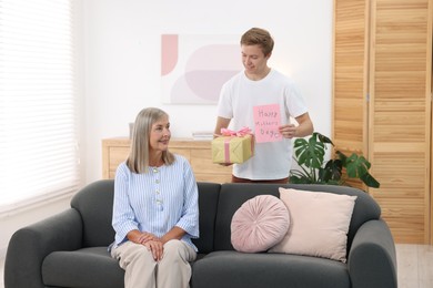 Photo of Happy Mother's Day. Son greeting his mom with gift and card at home