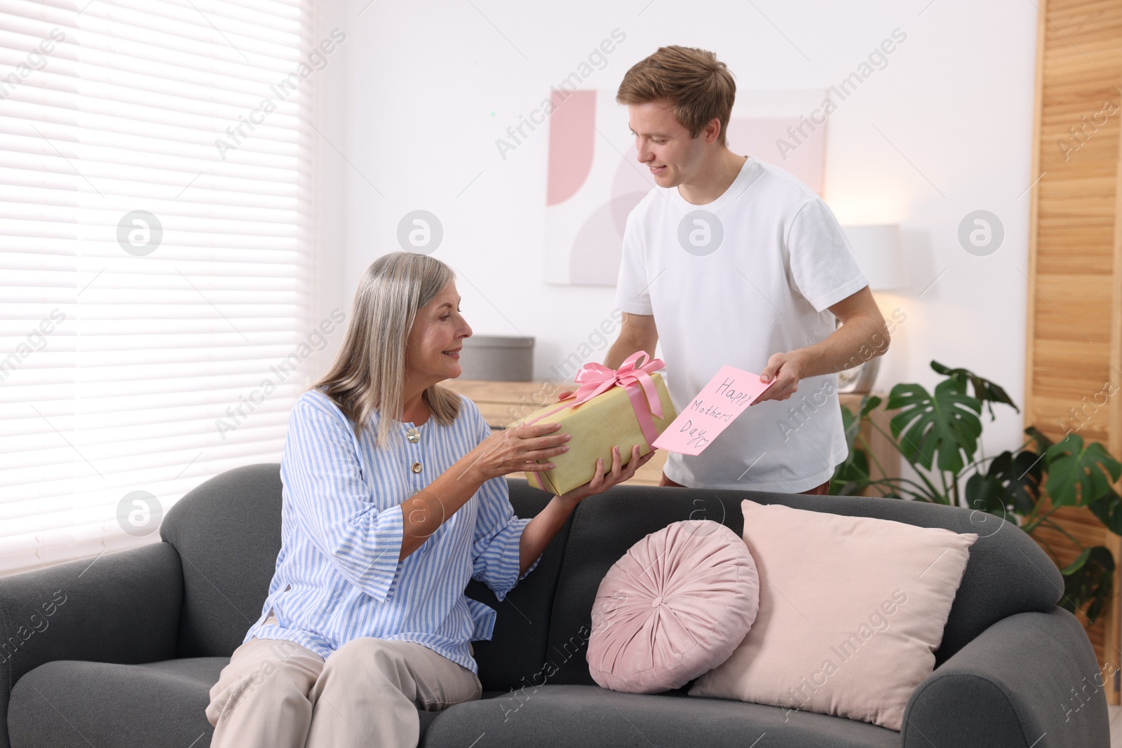 Photo of Happy Mother's Day. Son greeting his mom with gift and card at home