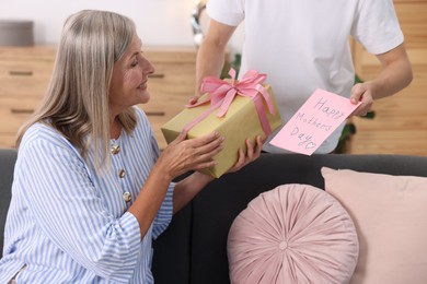 Photo of Happy Mother's Day. Son greeting his mom with gift and card at home, closeup