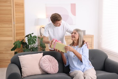Photo of Happy Mother's Day. Son greeting his mom with gift at home
