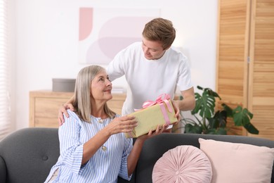 Photo of Happy Mother's Day. Son greeting his mom with gift at home