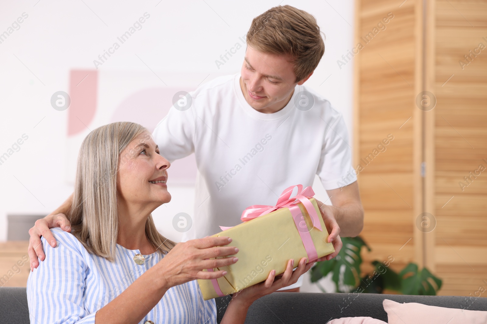 Photo of Happy Mother's Day. Son greeting his mom with gift at home