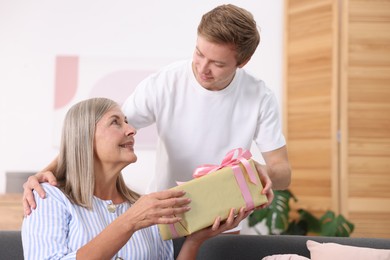 Photo of Happy Mother's Day. Son greeting his mom with gift at home