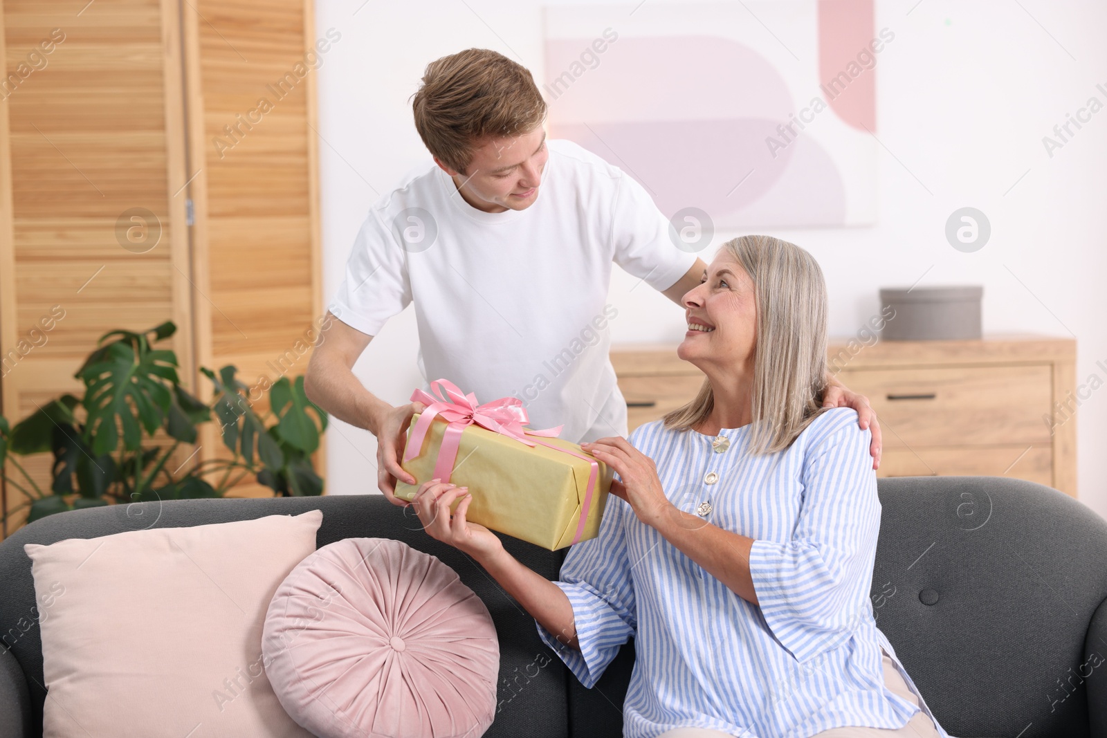 Photo of Happy Mother's Day. Son greeting his mom with gift at home