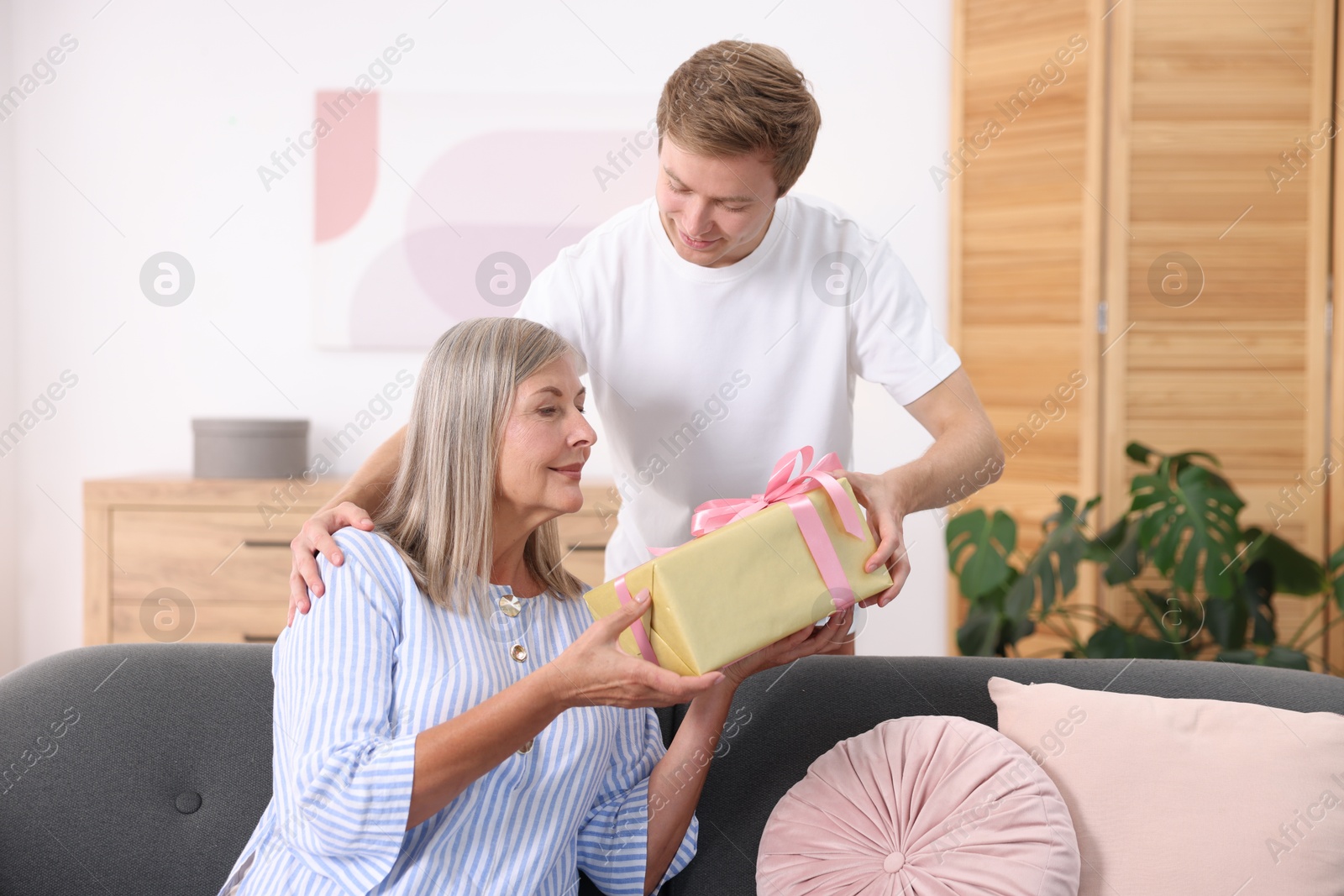 Photo of Happy Mother's Day. Son greeting his mom with gift at home