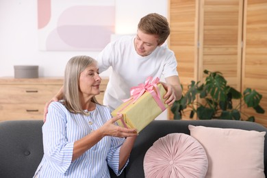 Photo of Happy Mother's Day. Son greeting his mom with gift at home
