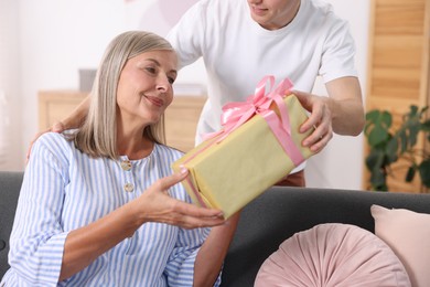 Photo of Happy Mother's Day. Son greeting his mom with gift at home, closeup