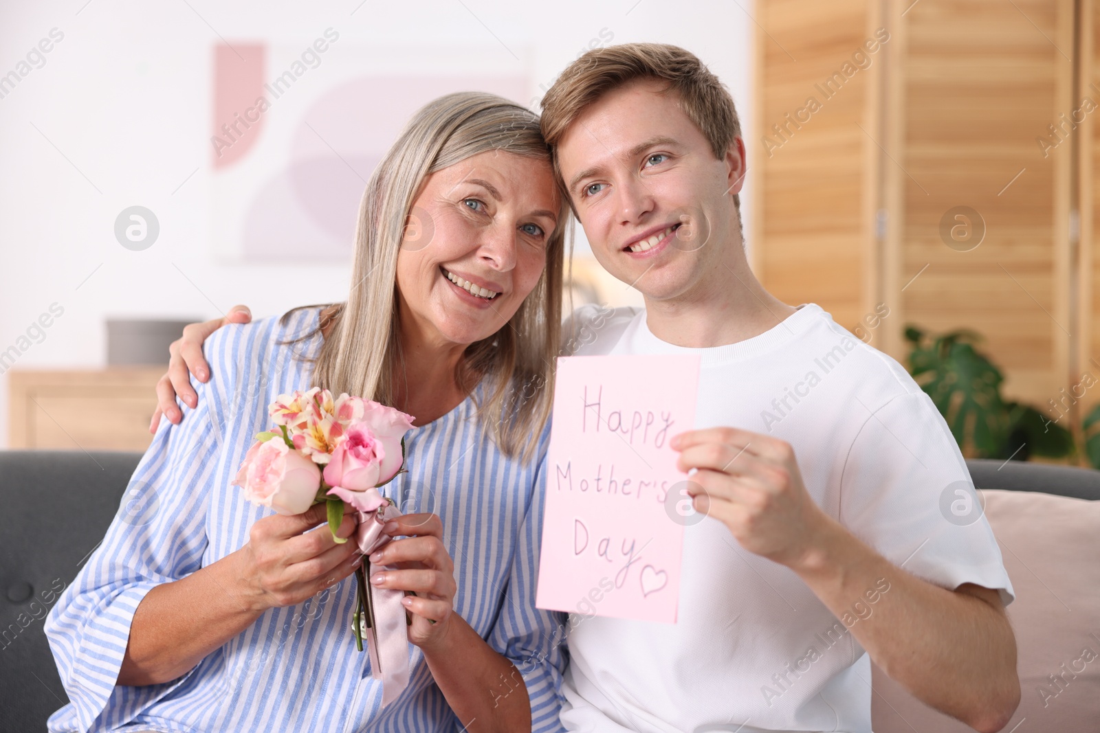 Photo of Happy Mother's Day. Son greeting his mom with bouquet of flowers and card at home