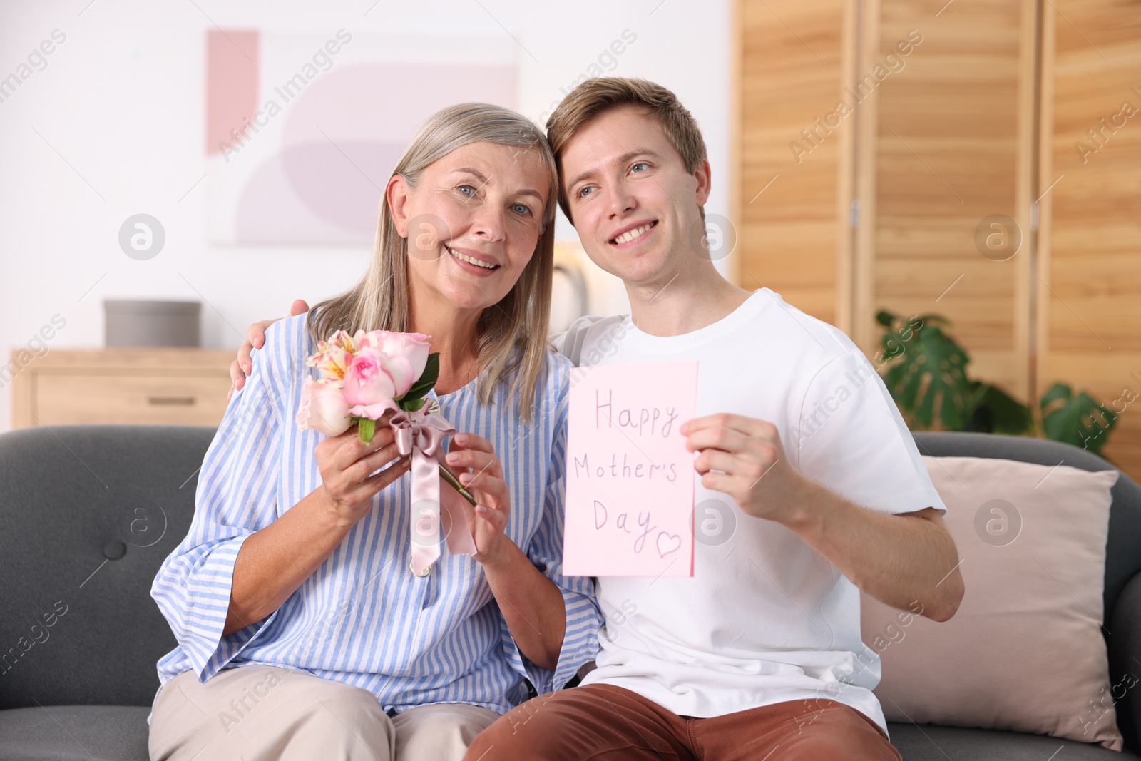 Happy Mother's Day. Son greeting his mom with bouquet of flowers and card at home Photo of Happy Mother's Day. Son greeting his mom with bouquet of flowers and card at home