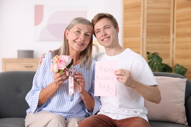 Photo of Happy Mother's Day. Son greeting his mom with bouquet of flowers and card at home