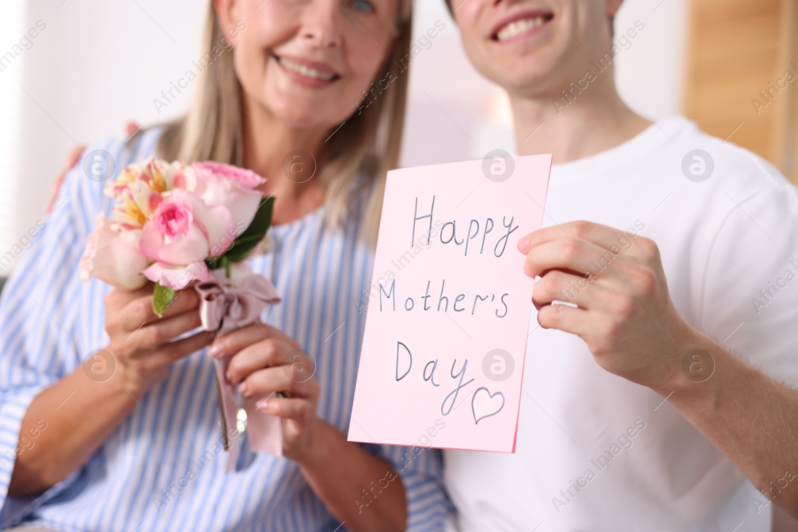 Photo of Happy Mother's Day. Son greeting his mom with bouquet of flowers and card at home, selective focus