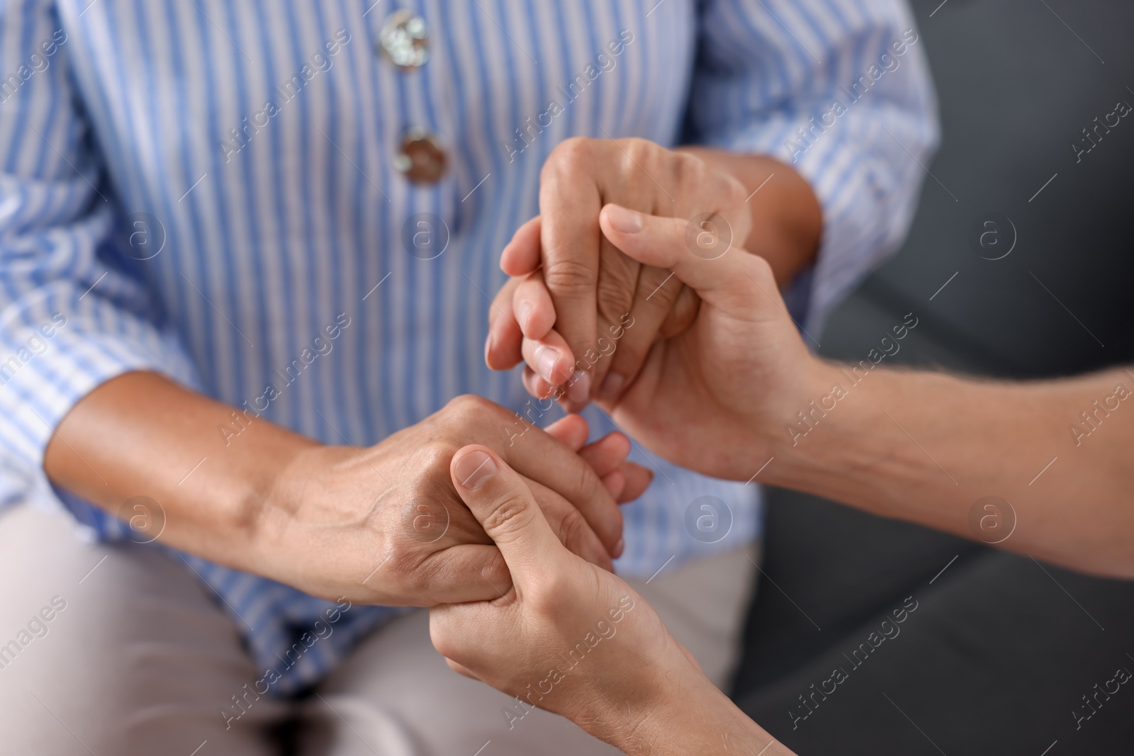 Photo of Son and his mother holding hands indoors, closeup
