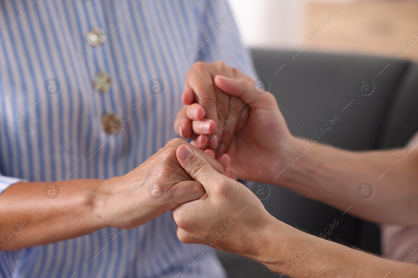 Photo of Son and his mother holding hands indoors, closeup