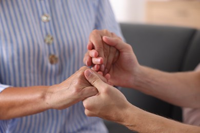 Photo of Son and his mother holding hands indoors, closeup