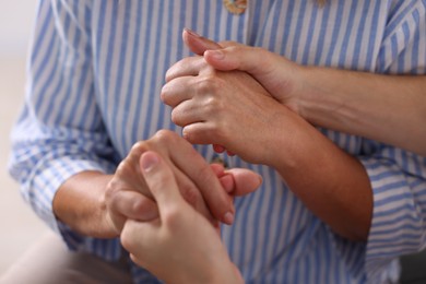Photo of Son and his mother holding hands indoors, closeup