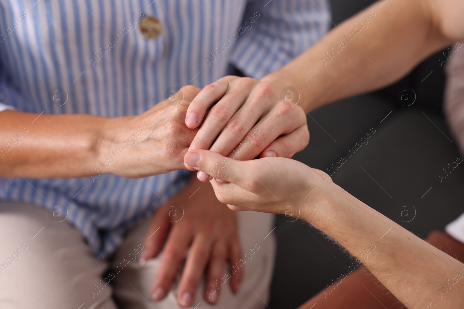 Photo of Son and his mother holding hands indoors, closeup