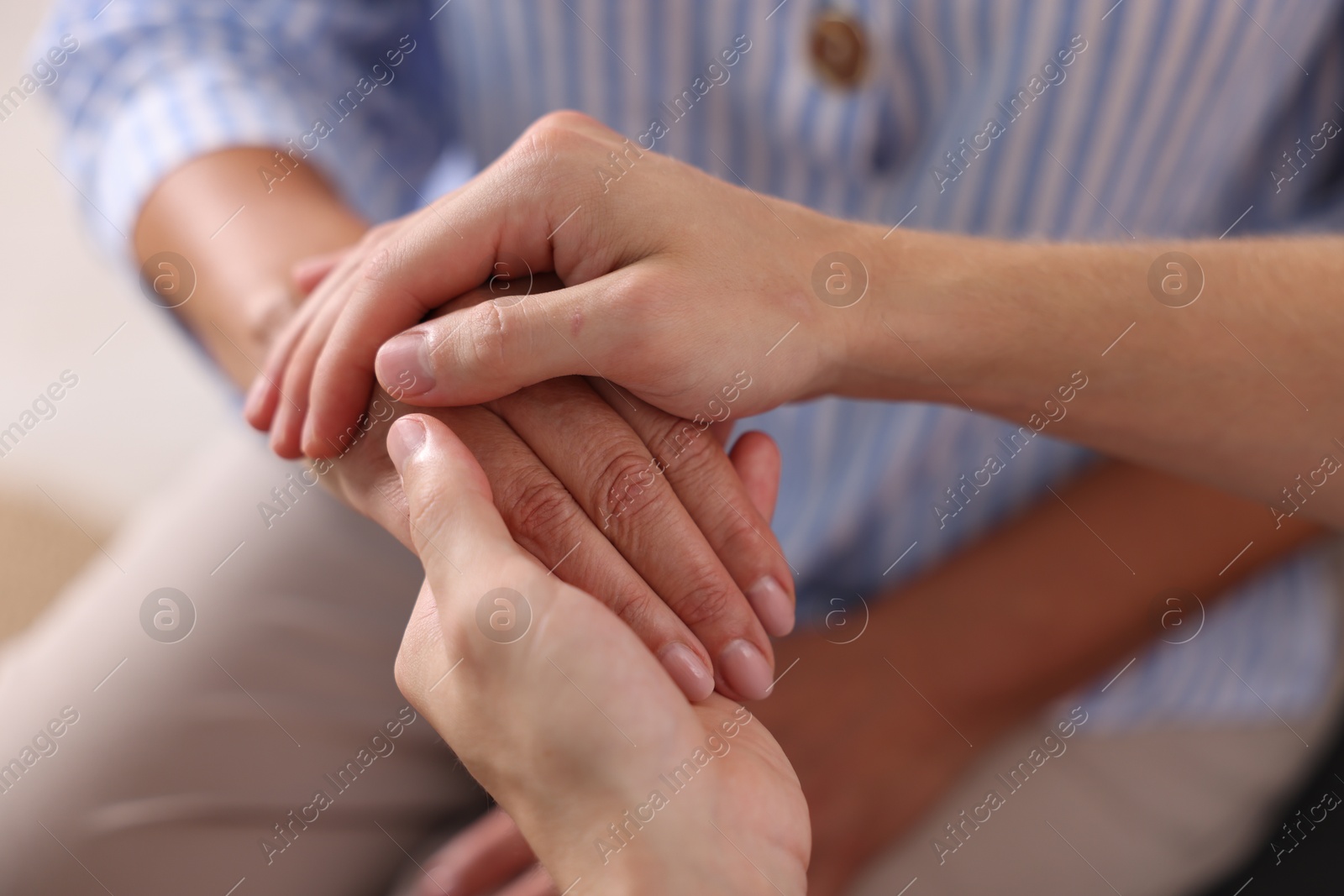 Photo of Son and his mother holding hands indoors, closeup