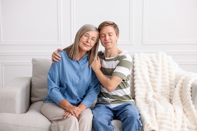 Photo of Son and his mother spending time together on sofa at home