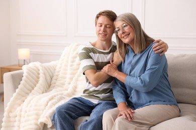 Photo of Happy son and his mother spending time together on sofa at home. Space for text