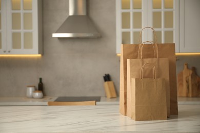 Photo of Paper bags on white marble table in kitchen. Space for text
