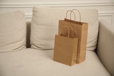 Photo of Paper bags on sofa at home. Space for text