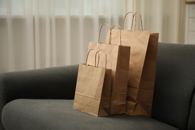 Photo of Paper bags on sofa at home. Space for text