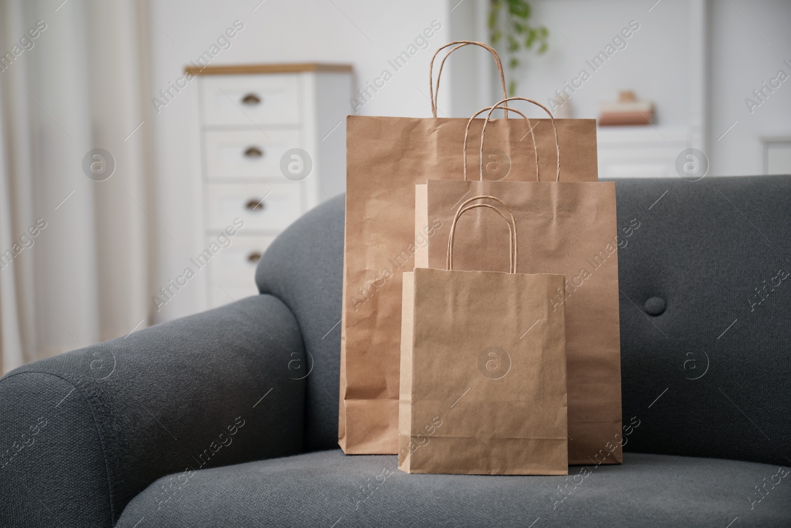 Photo of Paper bags on sofa at home. Space for text