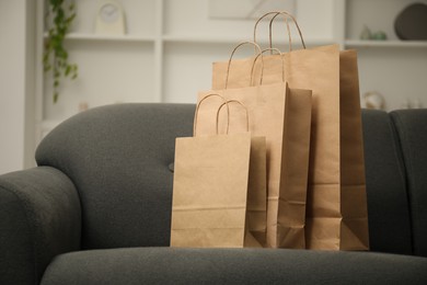 Photo of Paper bags on sofa at home. Space for text