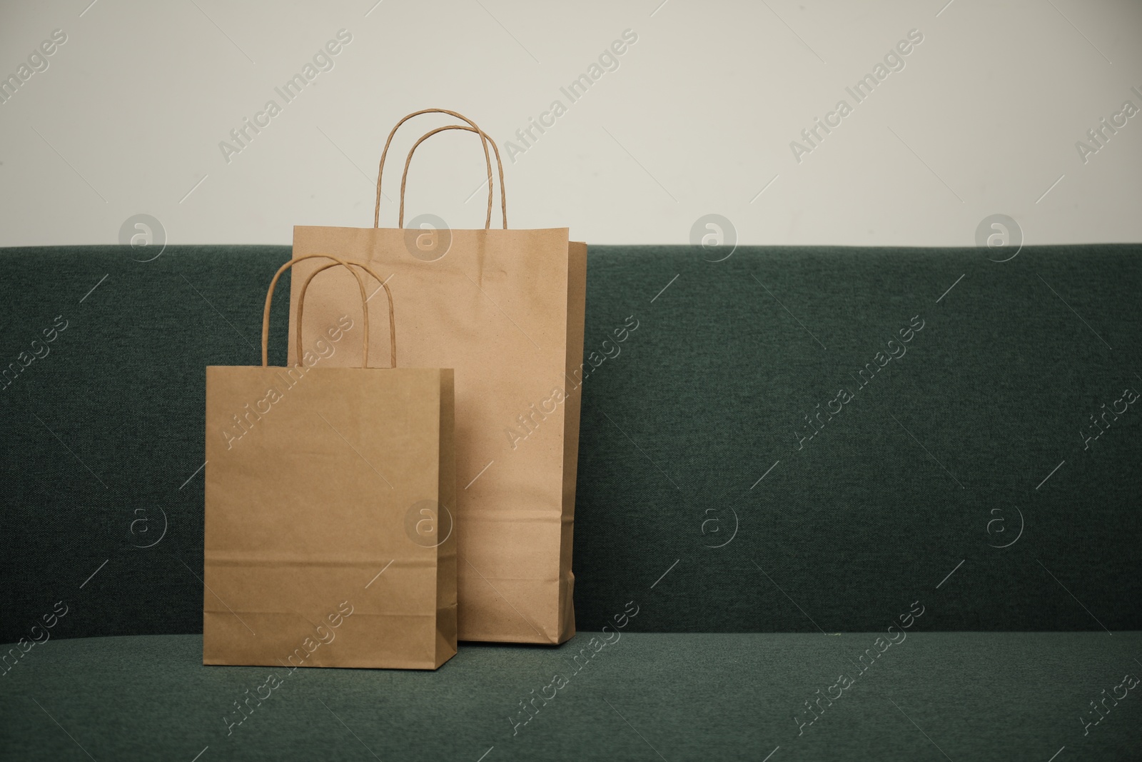 Photo of Paper bags on sofa at home. Space for text